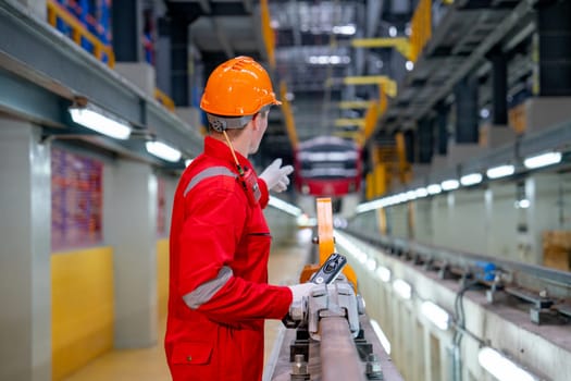 Back of professional technician worker with safety uniform point to the electrical or sky train in factory workplace.