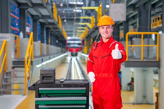 Professional technician worker stand with thumbs up and look at camera with smiling in electrical or sky train factory workplace.
