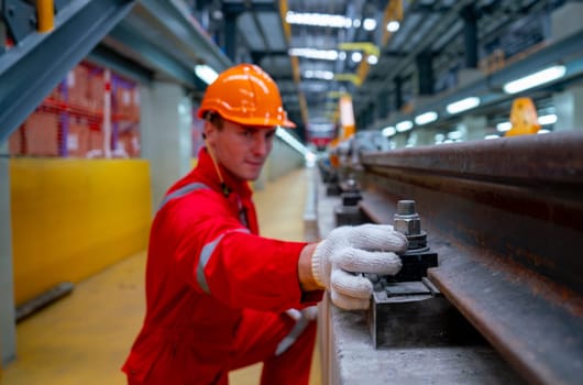 Close up hands of Caucasian technician hold hex nut and screw of railroad tracks of electrical or sky train during check and fix the problem in factory workplace.