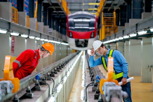 Professional engineer and technician worker look and check function of railroad tracks of electrical or sky train in factory workplace.