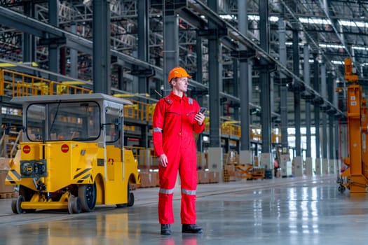 Professional technician worker stand near factory truck and hold mobile phone also look forward in electrical or metro train factory.