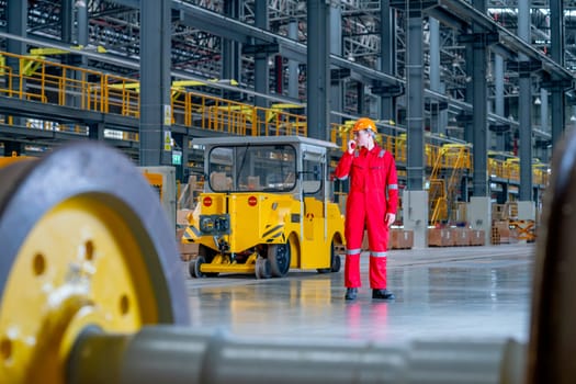 Professional technician worker stand near factory truck and use walkie talkie to contact his coworker in electrical or metro train factory.