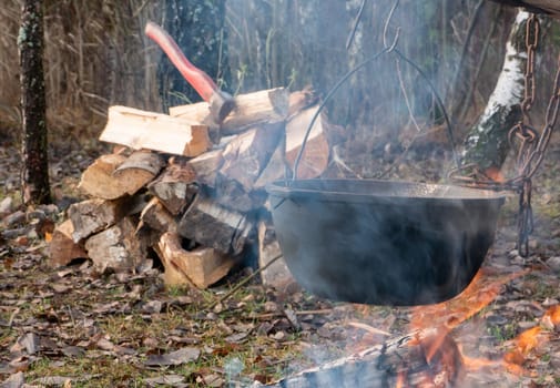 Black cauldron on a fire with boiling food on vacation in the forest.Touristic metal bowler pot. Cooking at the campsite