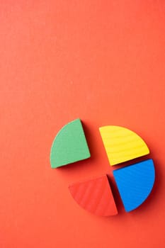 Colorful wooden pie chart pieces on bright red background with copy space
