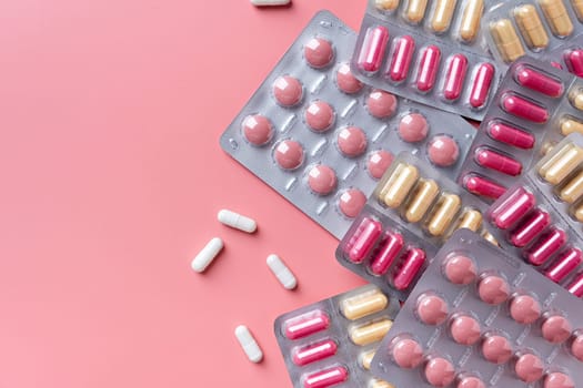 Flat lay composition with blisters on pink color background, copy space