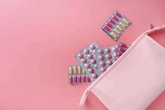 Flat lay composition with pink female cosmetic bag blisters on color background. womens health