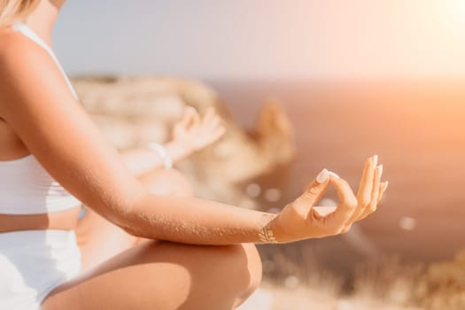 Woman meditating in yoga pose silhouette at the ocean, beach and rock mountains. Motivation and inspirational fit and exercising. Healthy lifestyle outdoors in nature, fitness concept.