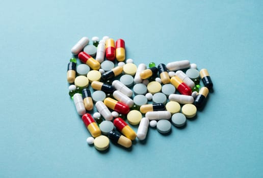 Pills forming heart shape on blue background, copy space