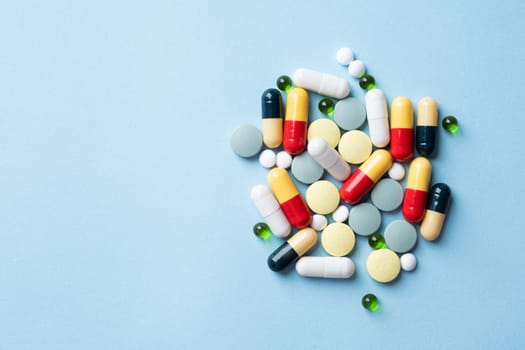 pile of Different pills on color blue background, flat lay