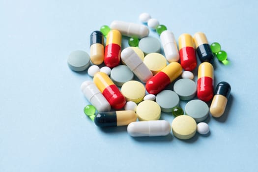 pile of Different pills on color blue background, flat lay