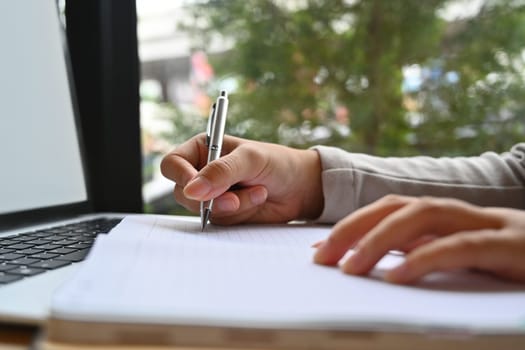 Closeup female manager taking notes planning start up, updating schedule at workplace