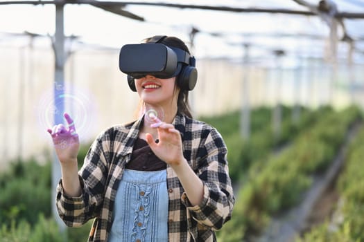 Farmer wearing VR headset for controlling process in greenhouse cultivation. Modern and smart agriculture concept
