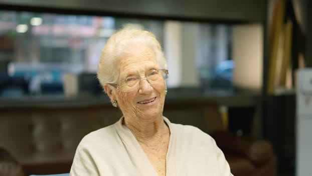 Close-up picture of a senior woman smiling at camera sitting in a nursing home