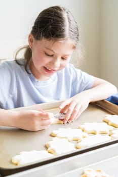 A heartwarming scene of a little girl carefully writing 'Sorry' on sugar cookies with food coloring, the cookies beautifully flooded with white royal icing.