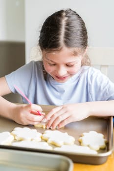 A heartwarming scene of a little girl carefully writing 'Sorry' on sugar cookies with food coloring, the cookies beautifully flooded with white royal icing.