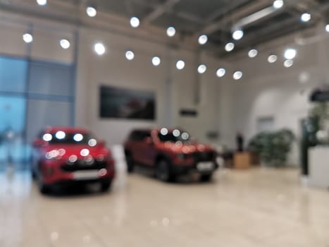 Blurred new car parked in modern showroom waiting for sales. Abstract background of blurred new cars dealership place.