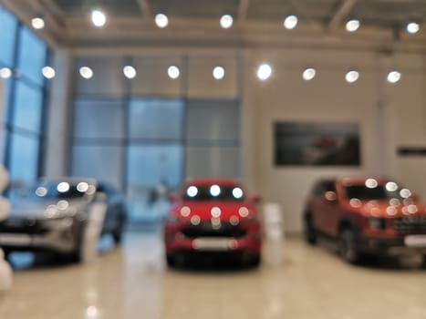 Blurred new car parked in modern showroom waiting for sales. Abstract background of blurred new cars dealership place.