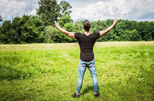 A man standing in a field with his arms outstretched