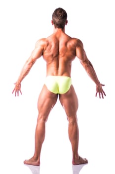 Full body shot of back of muscular young man standing and looking to a side, shirtless, wearing underwear