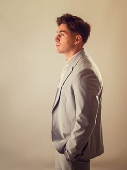 Attractive elegant young man with business suit, on white, looking away, seen sideways