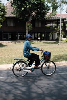 Jakarta, Indonesia - October 2 2023: Elderly Man in Blue Cycling