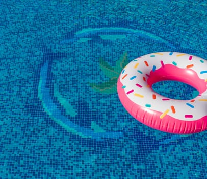 Whimsical inflatable ring, fashioned after a doughnut, rests atop the serene swimming pool