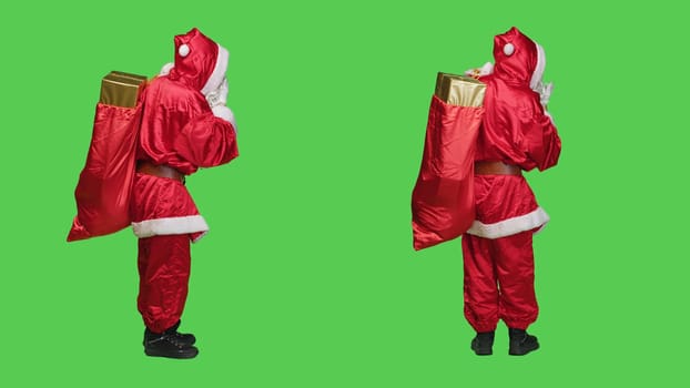 Sweet saint nick sends air kisses to spread romance and chrsitmas holiday spirit, acting flirty and cute over full body greenscreen backdrop. Person dressed as santa claus character in costume.
