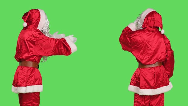 Santa cosplay giving air kisses on camera, doing sweet gesture over greenscreen background in studio. Young adult in red costume acting flirty and romantic with someone, christmas eve.