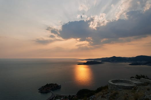 Orange sunset over the mountains and the island of Sveti Stefan. Montenegro. High quality photo