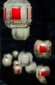 Abstract image of red and white lights encased in ice, with a blurred background, creating a cool and mysterious atmosphere.