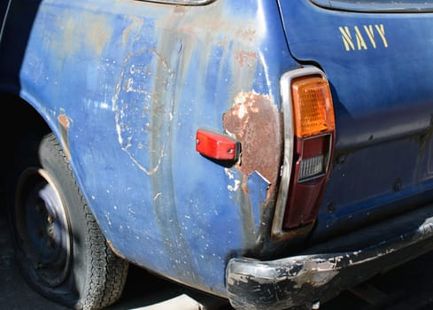 The rear left corner of an old navy car.