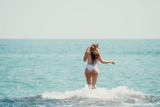 Woman sea yoga. Back view of free calm happy satisfied woman with long hair standing on top rock with yoga position against of sky by the sea. Healthy lifestyle outdoors in nature, fitness concept.