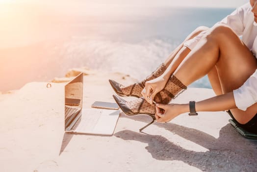 Happy girl doing yoga with laptop working at the beach. beautiful and calm business woman sitting with a laptop in a summer cafe in the lotus position meditating and relaxing. freelance girl remote work beach paradise