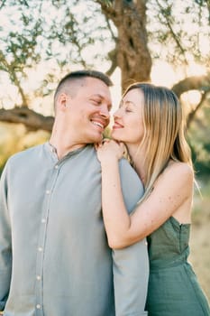 Young woman put her hands and chin on the shoulder of man who turned his head towards her. High quality photo