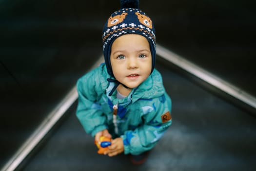 Little girl with a toy stands in an elevator car, looking up. High quality photo