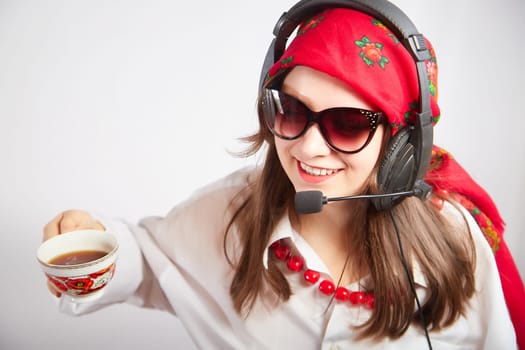 Portrait of young girl in a bright red scarf and large headphones with a microphone. A woman who is radio or television presenter with cap of tee. Funny female telecom operator. Freelancer at work