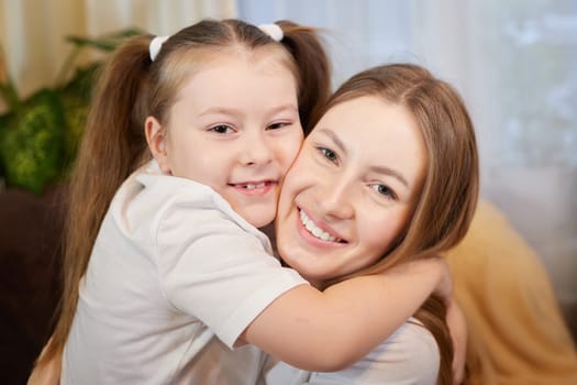 Happy loving family. Mother and her teenager daughter child girl playing and hugging in living room with flower