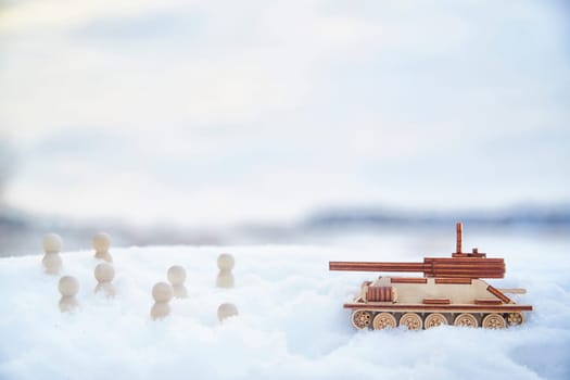 Wooden toy tank and little men in the snow. Russia and Ukraine are at war in winter. Encirclement, retreat, attack, victory