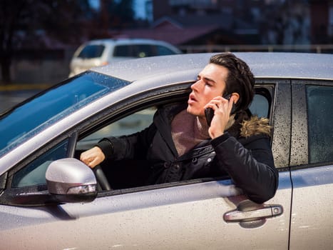 A man sitting in a car talking on a cell phone