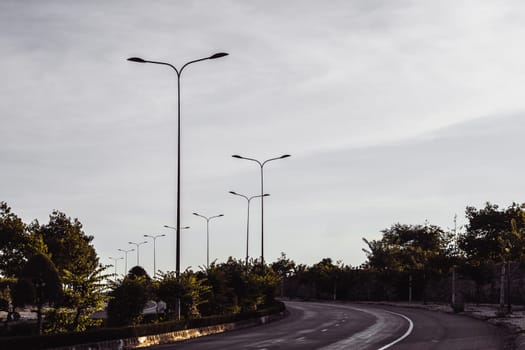 Highway curve road overpass nature landscape background dark tone mist day time street tall lanterns trees bushes sideway.