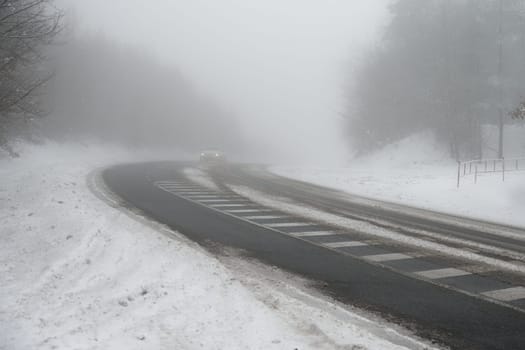 Bad weather driving - foggy hazy country road. Motorway - road traffic. Winter time. Autumn - fall.  Snow and frost on the road in winter.