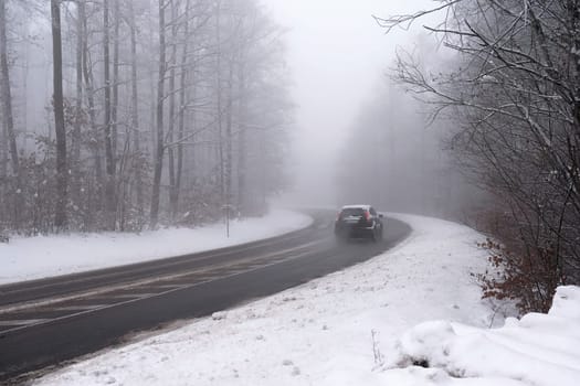 Cars in the fog. Bad winter weather and dangerous automobile traffic on the road. Light vehicles in foggy day.