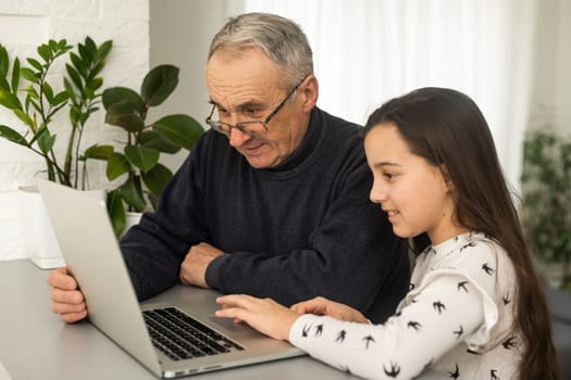Portrait of grandfather and granddaughter doing homework with laptop