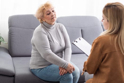 Depressed senior woman talking with female psychologist.