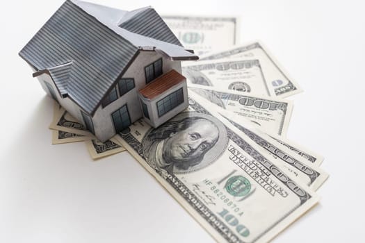 Miniature house model with banknotes on a wooden table, selective focus. Home loan concept