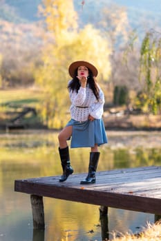 Autumn lake woman. She stands by a pond on a wooden pier in autumn and admires nature. The concept of tourism, weekends outside the city