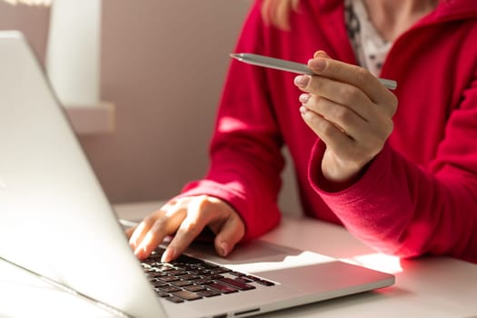 Hand of freelancer pointing on laptop screen with pen at desk