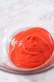 Mixing ingredients in a large glass mixing bowl to make homemade royal icing.