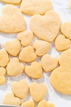 Decorating heart-shaped sugar cookies with pink and white royal icing for Valentine's Day.