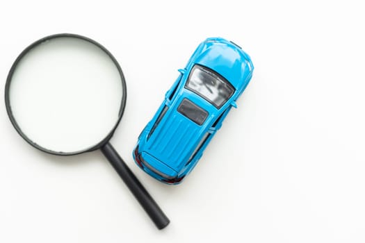 Toy car model and magnifying glass on white background. High quality photo